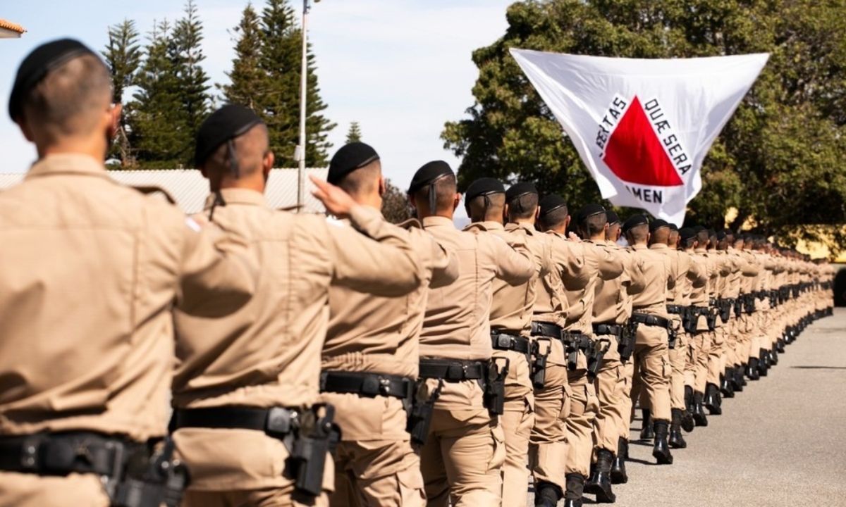 Militares em fila, de frente à bandeira de Minas